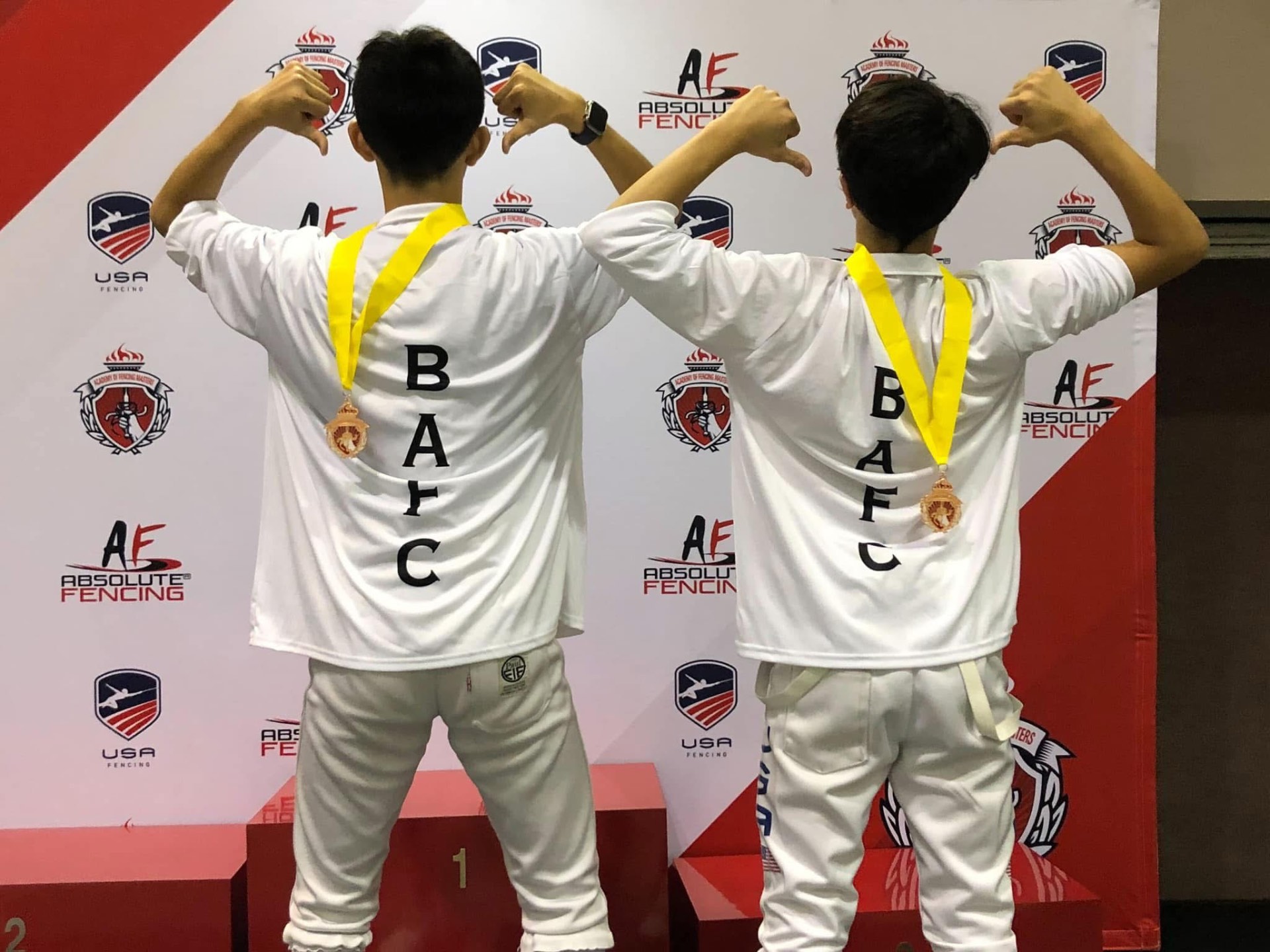 Two BAFC fencers celebrating on the podium with medals